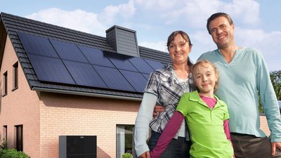 Eine kleine Familie, im Hintergrund ist ein Haus mit einer Photovoltaikanlage