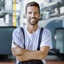 Ein Mann in Arbeitskleidung mit verschraenkten Armen